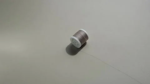 A spool of pastel-coloured sewing thread rolls after the unraveled thread Stock Footage 213041513