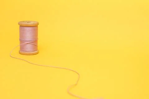 A spool of pink thread on a yellow background Stock Photos