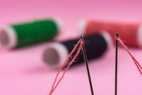 Spool with red thread and needle on pink background Stock Photos