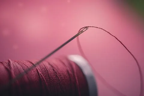 Spool of red thread and needle on red background. Stock Photos