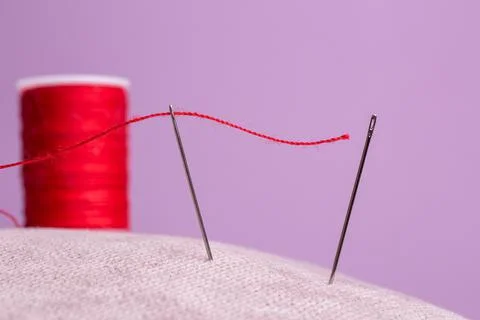 Spool with red thread and needle on pink background Stock Photos