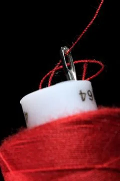 A spool of red thread and a needle 스톡 사진