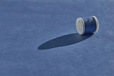 A spool of sewing thread of a beautiful pale blue color lies with an unwound  스톡 사진