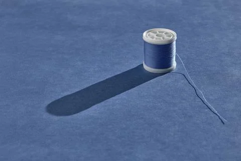 A spool of sewing thread of a beautiful pale blue color stands against a harm 스톡 사진