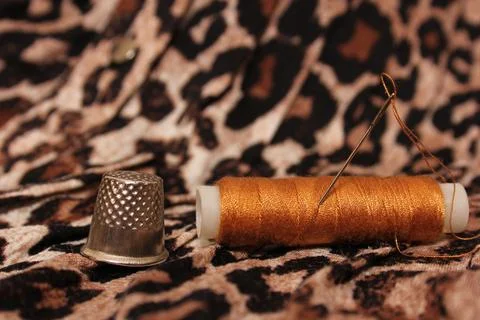 Spool of Tan Thread on Leopard Print Fabric Stock Photos