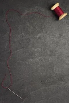 Spool of thread and needle on slate stone Stock Photos