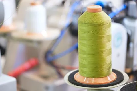 Spool of thread on an industrial sewing machine in a garment factory, industr Stock-Fotos