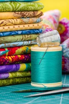 Spool of thread with needle and thimble on the background fabric Stock-Fotos