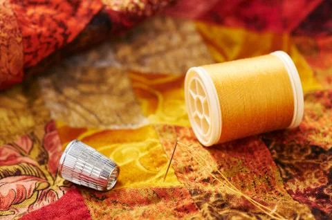 Spool of thread, needle and thimble on a quilt Stock Photos