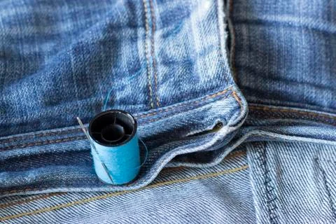 The spool of thread, needle, old jeans Foto stock