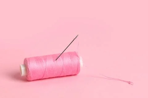 Spool of thread with needle on pink background Stock Photos