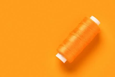 Spool of thread on orange background Stock Photos
