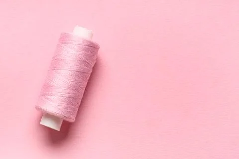Spool of thread on pink background 写真素材
