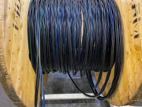 A spool of various wires is currently resting on a sturdy wooden spool, cre.. Stock Photos