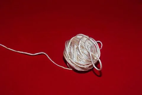 A spool of white synthetic thread on a red background Stock Photos
