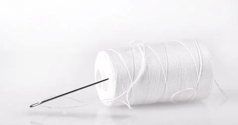 Spool with white thread and a needle. Stock Photos