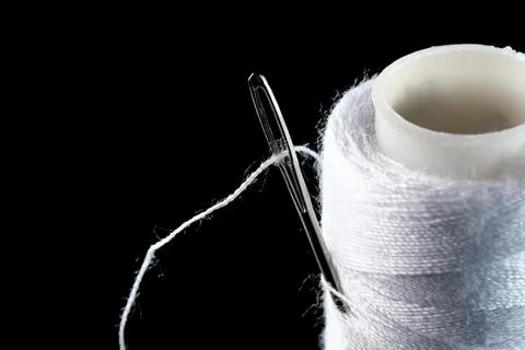 A spool of white thread and a needle 스톡 사진