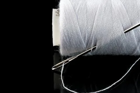 A spool of white thread and a needle 스톡 사진