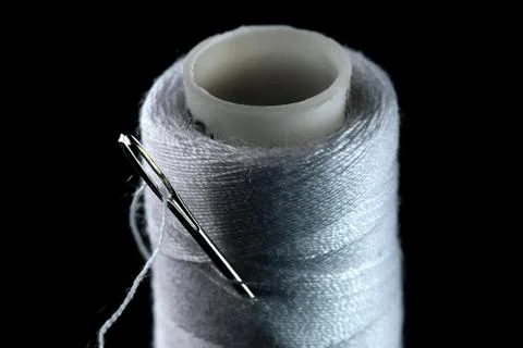 A spool of white thread and a needle Foto stock