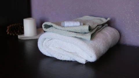 A spool of white thread lies on top of light green and white folded terry towels Photos