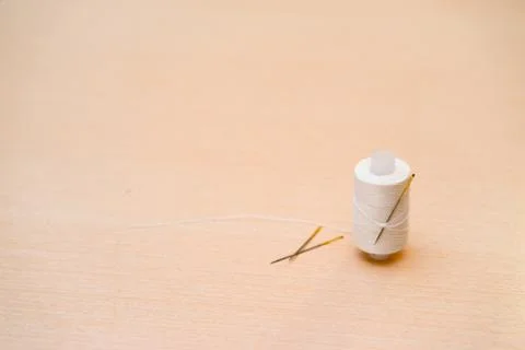 A spool of white thread with needle in the background. Stock Photos