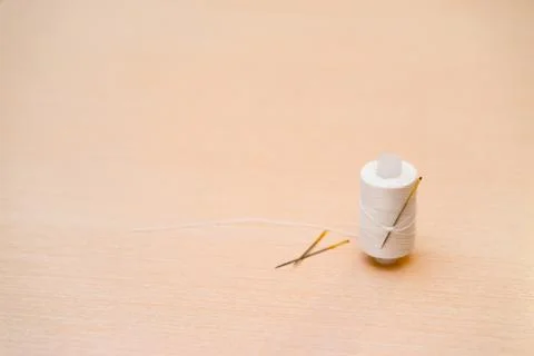 A spool of white thread with needle in the background. Stock Photos