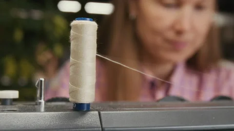 Spool of White Thread on Sewing Machine and Face of Seamstress at Work Stock Footage 315734350