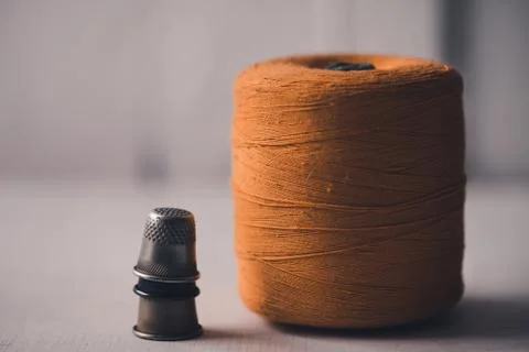 Spool of yellow old thread with thimbles staying on table closeup. Handmade. Stock-Fotos