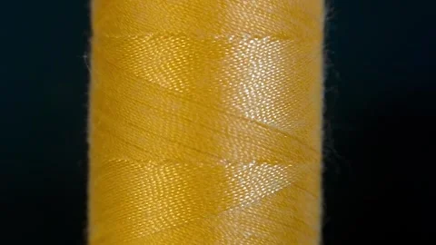 Spool of yellow threads for sewing on a black and light background Stock Footage 259883240