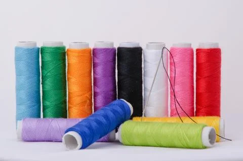 Spooled thread and sewing needle on white background Stock Photos