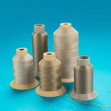 Spools of beige polyester thread on a blue background Stock Photos