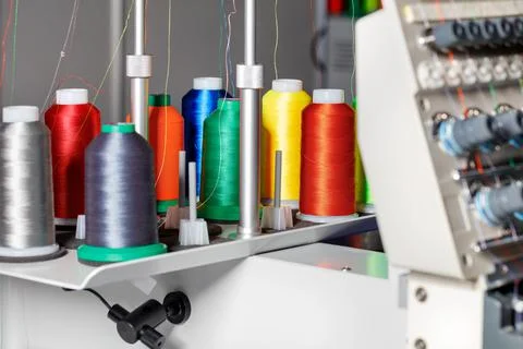 Spools of colored threads for industrial sewing and embroidery machines on a  Stock Photos