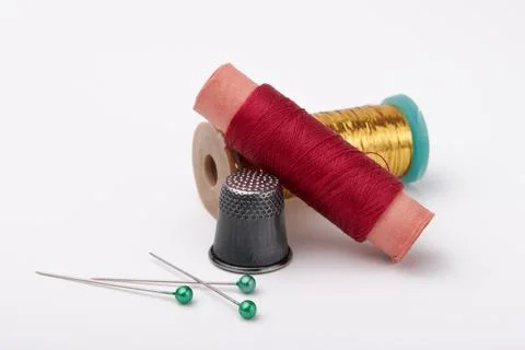 Spools with multi-colored thread, thimble and pins on a white background Stock Photos