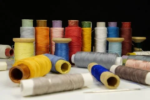 Spools with multi-colored threads on black background, close-up shot 库存照片