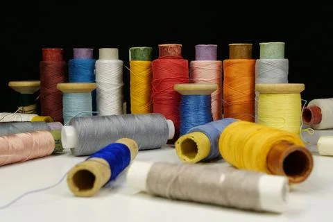 Spools with multi-colored threads on black background, close-up shot Photos