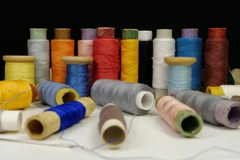 Spools with multi-colored threads on black background, close-up shot Stock Photos
