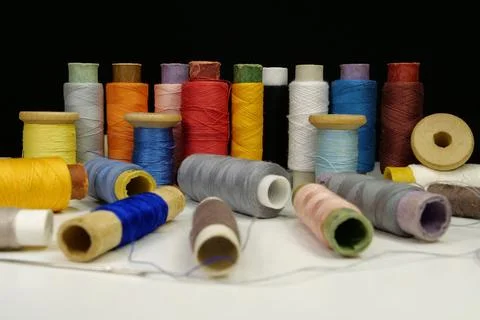 Spools with multi-colored threads on black background, close-up shot Stock Photos