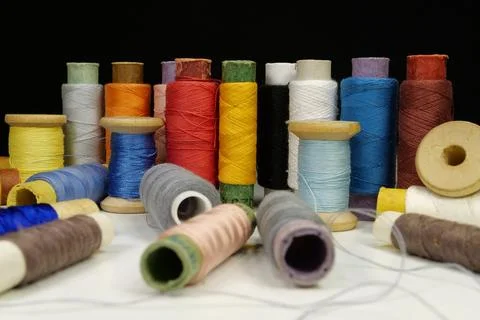 Spools with multi-colored threads on black background, close-up shot Photos