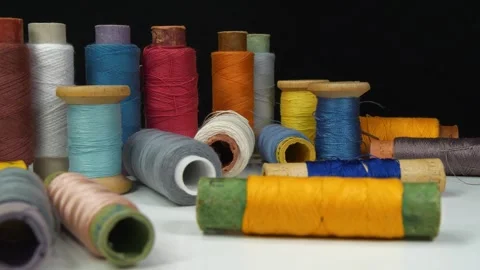 Spools with multi-colored threads lies on white table on black background Stock Footage 310011959