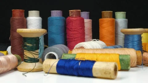 Spools with multi-colored threads rotates on black background, close-up shot Stock Footage 309646507