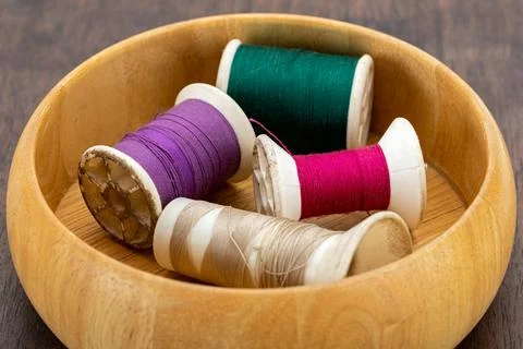 Spools of old cotton thread in different colors in a light brown wooden box.. Stock Photos