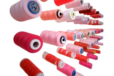 Spools of red and pink sewing thread arranged on white background. Colorful b Foto stock