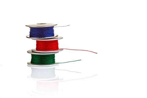 Spools of thread in blue, red, green colors on a white background Stock Photos
