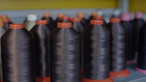 Spools of thread for sewing shoes in dark colors stand on a shelf. Stock Footage 123413888