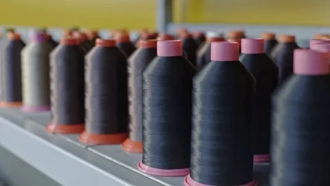 Spools of thread for sewing shoes in dark colors stand on a shelf. Stock Footage 123413892