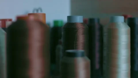 Spools of thread for sewing shoes in dark colors stand on a shelf Stock Footage 170550988