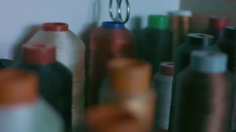 Spools of thread for sewing shoes in dark colors stand on a shelf Stock Footage 170551178
