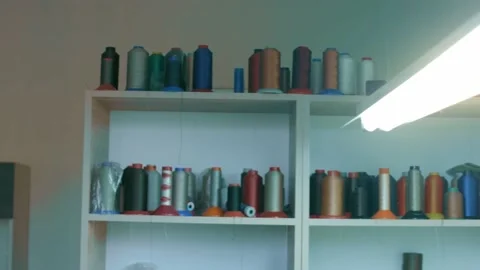 Spools of thread for sewing shoes in dark colors stand on a shelf Stock Footage 170551400