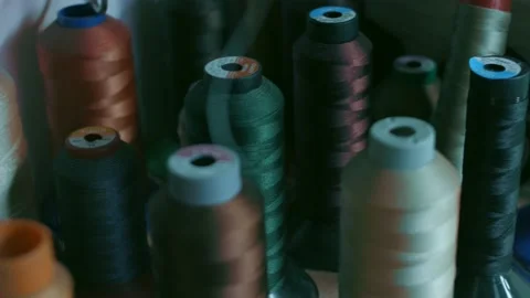 Spools of thread for sewing shoes in dark colors stand on a shelf Stock Footage 170552730