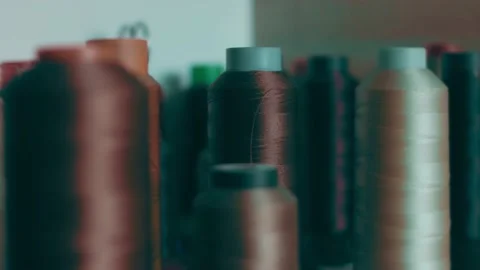 Spools of thread for sewing shoes in dark colors stand on a shelf Stock Footage 232615897